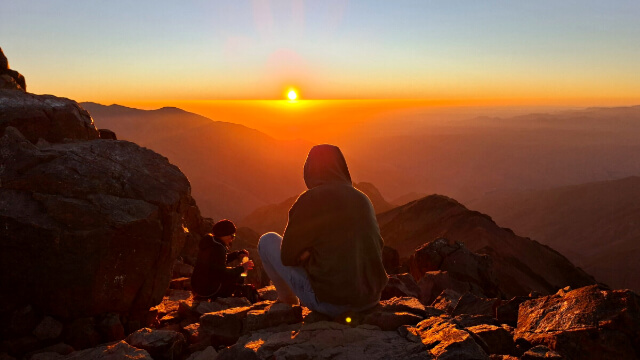 Marokko aktiv • Zwei Wanderer beobachten den Sonnenaufgang auf dem Toubkal in Marokko